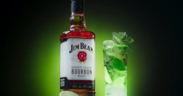 Uitzoomen shot: geïsoleerde fles Jim Beam bourbon drank met cocktail op de achtergrond, 4k 60p Prores HQ — Stockvideo