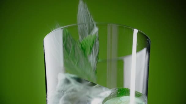 Blad van munt druppels op het highball glas met cocktail en ijsblokjes op de groene achtergrond, 1080p Prores HQ 240fps — Stockvideo