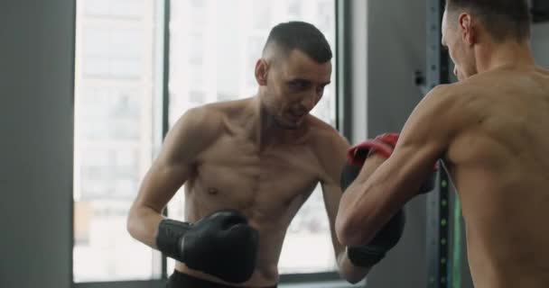 Bojovník v boxerských rukavicích cvičí své údery s trenérem ve zpomaleném filmu v tělocvičně, kickboxeři trénují, 4k 120fps Prores HQ — Stock video
