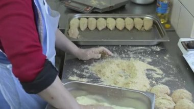 Şef Paneers pirzolasını ekmek kırıntılarına koyup damlayan tavaya koyuyor.
