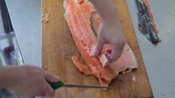 Cook corta el pescado en la tabla de madera con un cuchillo en la cocina — Vídeos de Stock