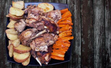 Siyah bir tabakta sebze ile kavrulmuş tavşan