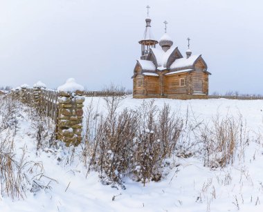 Şiddetli kar yağışından sonra ahşap bir kiliseyle kırsal alanda kış manzarası. 
