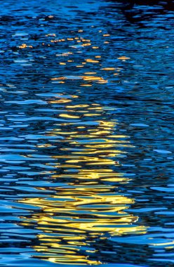 Bir fenerden yansıyan ışık ile akşam nehir suyu dokusu. 