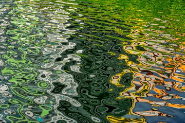 Rüzgarlı havada göletin sularındaki yüksek binaların yansıması..