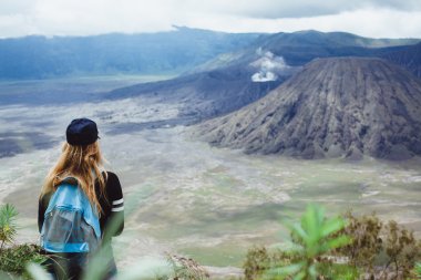 girl standing looking  at volcano
