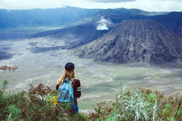 girl standing looking  at volcano