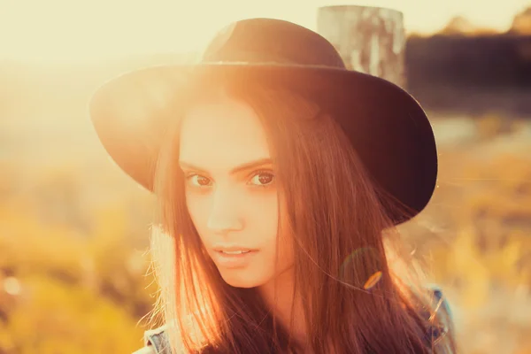 Chica en sombrero negro posando al atardecer — Foto de Stock