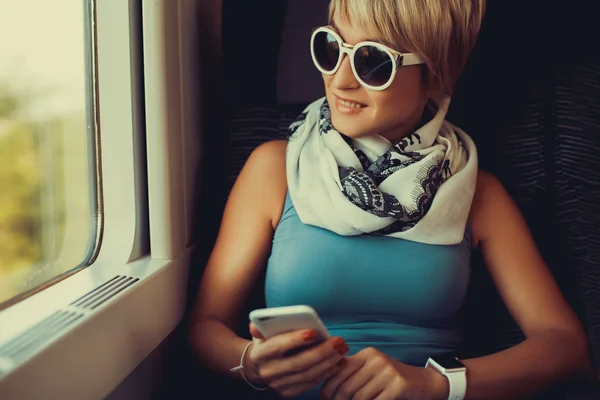 Bonita mujer mantiene el teléfono inteligente en las manos — Foto de Stock