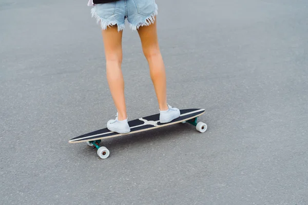 Young woman posing in street with skateboard — Stock Photo, Image