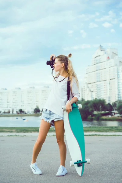 Giovane donna in posa in strada con longboard — Foto Stock