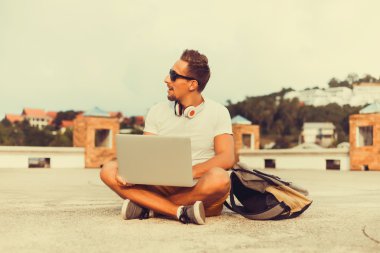 Dizüstü bilgisayarda çalışan genç adam.