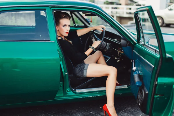 Hermosa chica sentada en un coche vintage — Foto de Stock