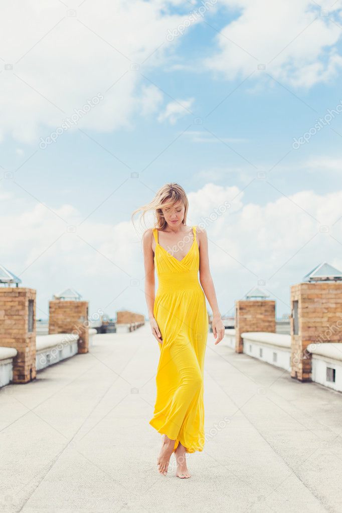 girl posing on the pier in yellow dress