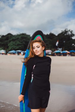girl in wetsuit with surfboard