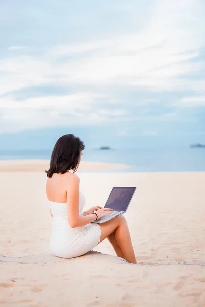 Mädchen arbeitet am Strand an einem Laptop — Stockfoto