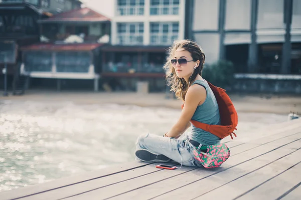 Chica en gafas de sol sentado en el muelle del mar — Foto de Stock