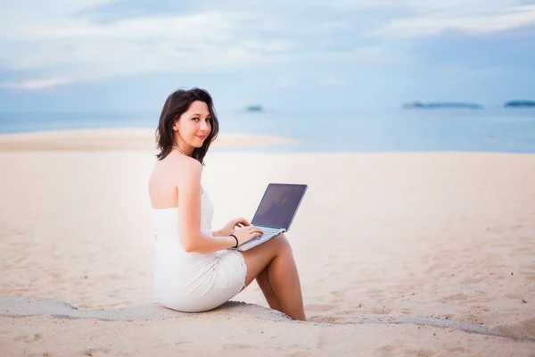 Sahilde bir dizüstü bilgisayarda çalışan kız — Stok fotoğraf