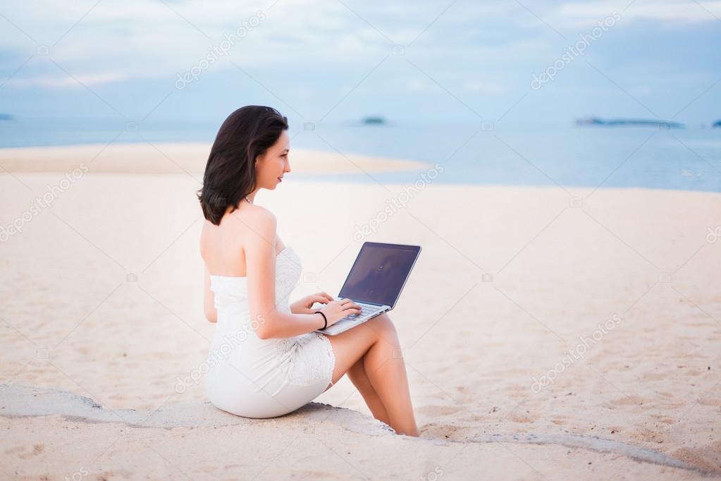 girl working on a laptop on the beach