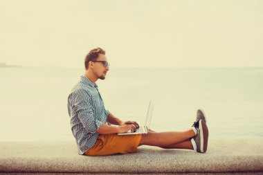 Dizüstü bilgisayarda çalışan genç adam.