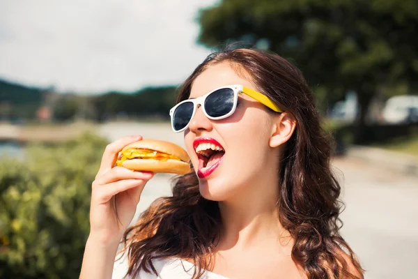 Girl in glasses eating fast food — Stock Photo, Image