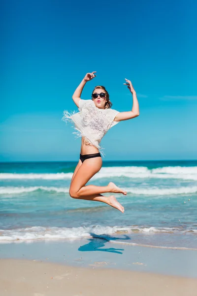 Mädchen in Brille springt am Strand — Stockfoto