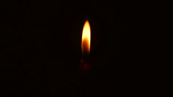 Одна свеча ярко горит на черном фоне — стоковое видео