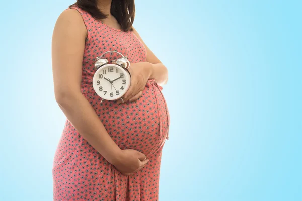 Mujer embarazada sosteniendo el reloj. Es la hora. sobre fondo azul suave — Foto de Stock