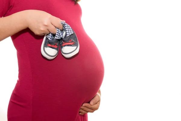 Zapatos pequeños para el feto en el vientre de la mujer embarazada i — Foto de Stock