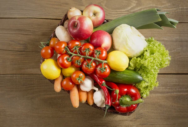 Cesto di vimini con frutta e verdura sul tavolo di legno — Foto Stock