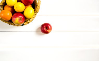 Beyaz ahşap masa üzerinde bir hasır sepet meyve