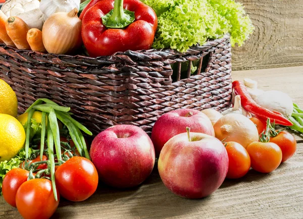Cesta de vime com frutas e legumes na mesa — Fotografia de Stock