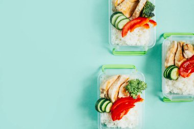 Beslenme çantalarının üst görüntüsü. İçinde yiyecek, pirinç, sebze ve yeşil arka planda meyve var. Metin için boş yer var.