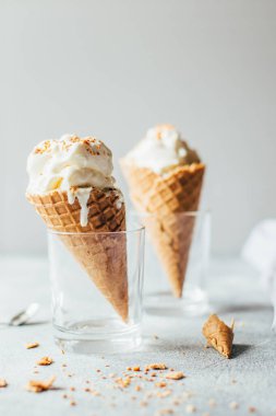 Gri bir masada gözleme kabında beyaz vanilyalı dondurma.