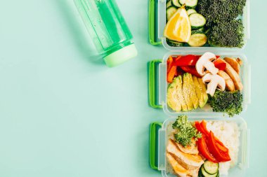 Beslenme çantalarının üst görüntüsü. İçinde yiyecek, pirinç, sebze ve yeşil arka planda meyve var. Metin için boş yer var.