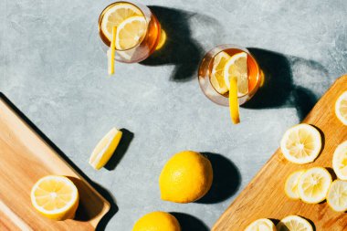 Alkollü kokteyl ve limonlu bardakların üst görüntüsü gri arka planda.
