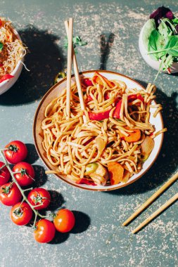 Tabaklarda et, sebze ve yeşil arka planda Çin yemek çubukları olan Çin eriştesi tabağı.