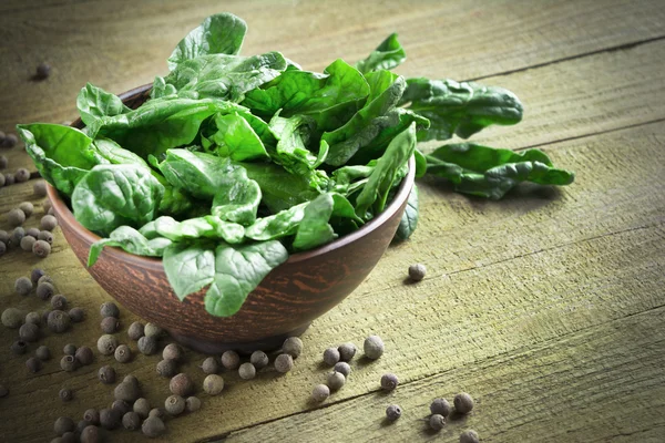 Spinach leaves in a bowl on a wooden table — Stock Photo, Image