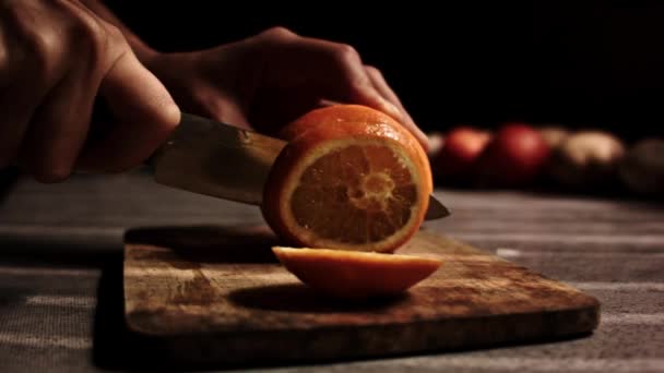 Вирізає апельсин на кухні — стокове відео