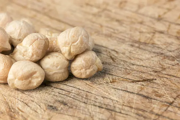 Uncooked chickpeas over wooden table close up. — Stock Photo, Image