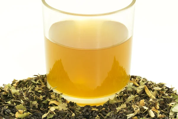 Glass cup of tea with some dried tea leaves. — Stock Photo, Image