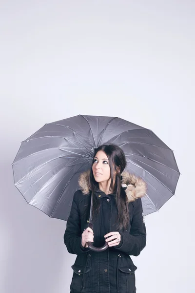 Gri arka plan üzerinde bir şemsiye tutan kadın