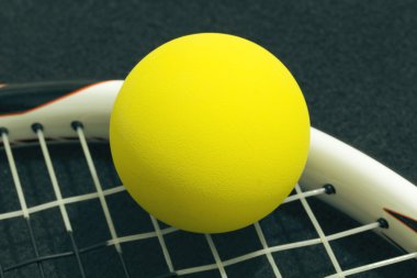 Racquetball on racket strings. Yellow frontenis ball laying on r clipart