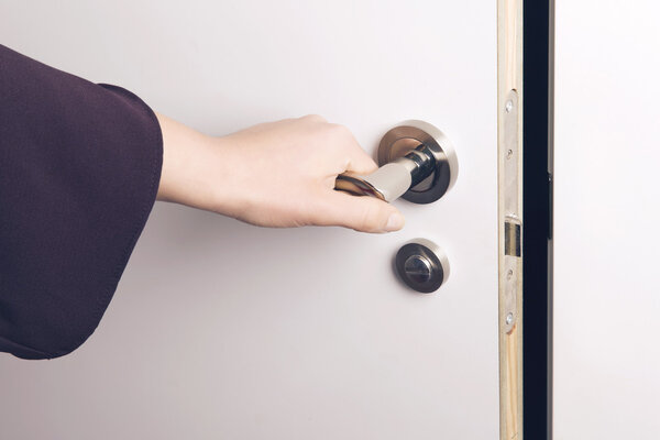 Woman hand opens a door to a dark and unknown room.