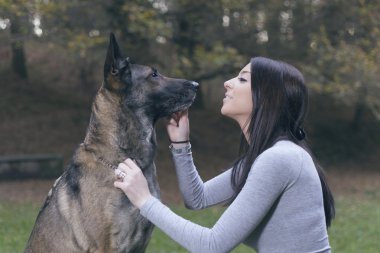 Genç kadın ile onun malinois köpek parkta oynarken.