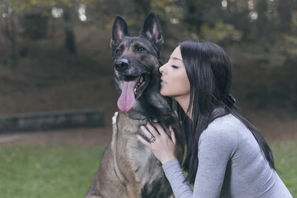 Genç kadın ile onun malinois köpek parkta oynarken.