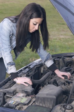 Düzeltmeye çalışarak kırık bir araba yanında duran kadın