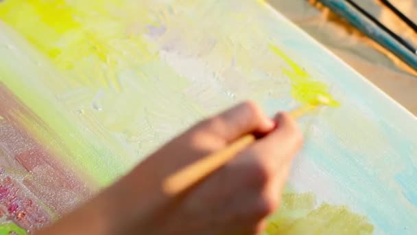 Joven artista pintando un cuadro con pinturas al óleo sobre el lienzo natural — Vídeos de Stock