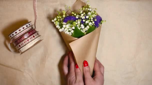 Glücklicher Blumenhändler, der Blumen in Bastelpapier einwickelt und sie dem Mann im Blumenladen schenkt. professionelle Floristik Materialien auf dem Tisch. Ansicht von oben — Stockvideo