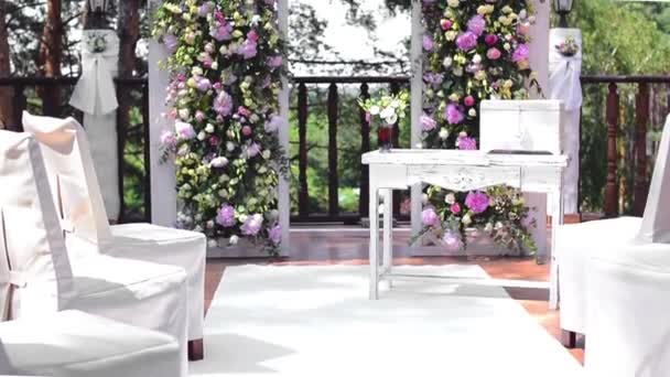 Arco para la ceremonia de boda, decorado con flores de peonías rosadas y vegetación, se encuentra en un bosque de pinos en la terraza — Vídeos de Stock